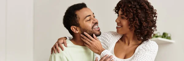Ein freudiges afroamerikanisches Paar teilt Lachen und Zuneigung in seiner stilvollen Wohnung, Banner — Stockfoto