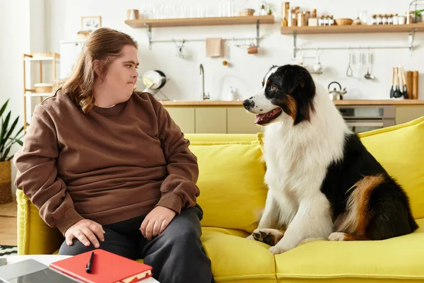 A young woman with Down syndrome shares a joyful moment with her dog on a sunny day at home. — Stock Photo
