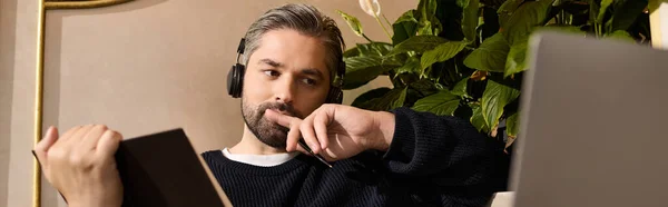 A handsome, mature man reflects thoughtfully while seated among lush greenery, dressed stylishly. — Stockfoto