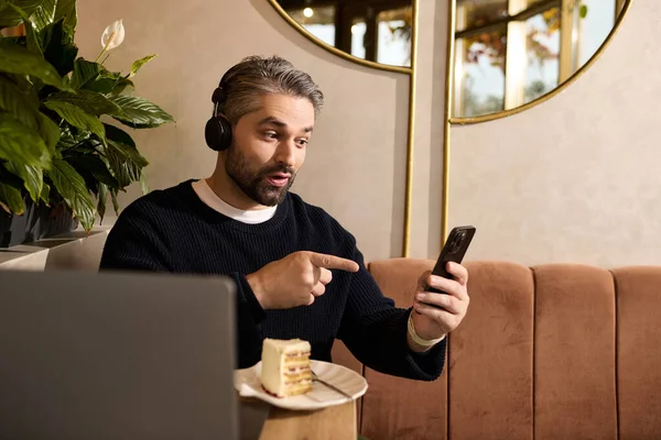 Красивый мужчина показывает волнение, разговаривая по телефону в модном кафе. — стоковое фото