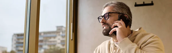 A handsome man in stylish clothes talks on his phone while gazing at the city. — Stockfoto