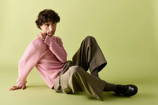 Selbstbewusster Mann sitzt auf dem Boden und zeigt trendige Mode in beruhigender Farbgebung. — Stockfoto