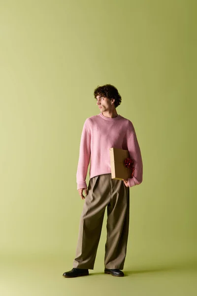 Handsome man in trendy outfit stands confidently with a folder in hand in a vibrant setting. — Stock Photo