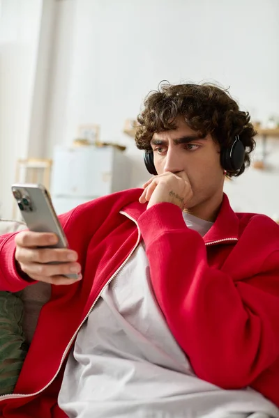 Красивий чоловік в модному вбранні закарбований у своєму смартфоні, оточений невимушеною атмосферою. — стокове фото