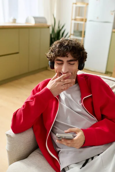 Стильний чоловік посміхається, слухаючи музику, розслаблений на затишному дивані в сучасному житловому просторі. — стокове фото