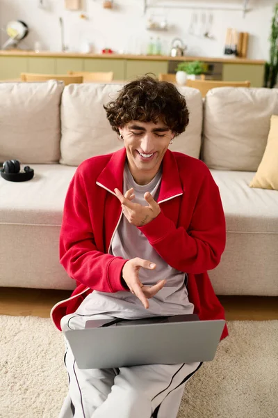 Un uomo affascinante gode di una conversazione virtuale con gli amici mentre si rilassa su un accogliente divano. — Foto stock