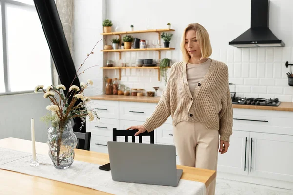 Блондинка в зручному одязі відпочиває вдома, насолоджуючись затишним способом життя за своїм столом. — стокове фото