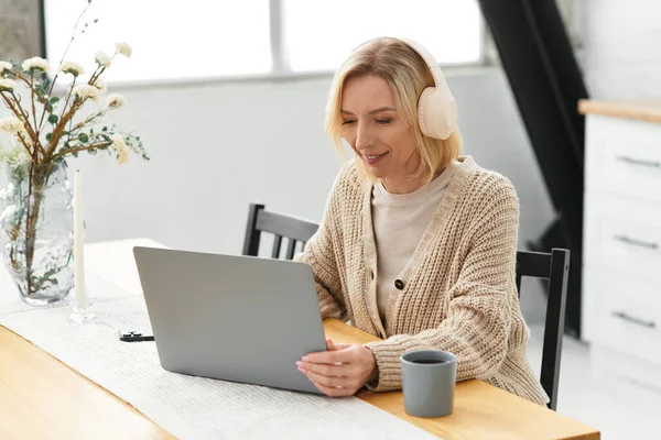 Блондинка відпочиває в зручному одязі, використовуючи свій ноутбук і чай. — стокове фото