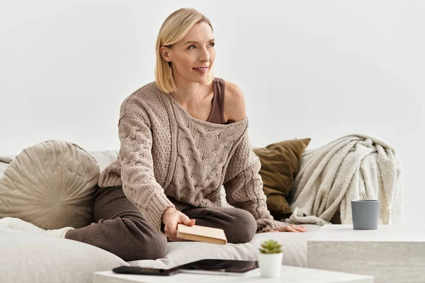 Блондинка відпочиває на дивані в затишному одязі, оточеному сучасним декором. — стокове фото