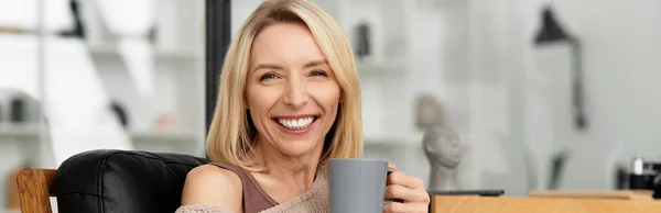 Блондинка расслабляется в своей уютной квартире, потягивая из теплой кружки, баннер — стоковое фото