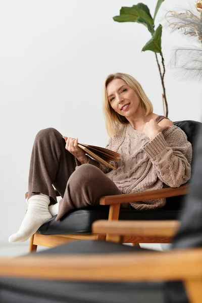 Blonde woman enjoys a quiet moment in her modern apartment, wrapped in comfort on a winter day. — Stock Photo