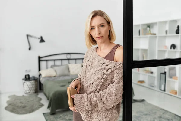 Blonde woman relaxes in comfortable clothing, surrounded by a cozy and stylish apartment decor. — Stock Photo