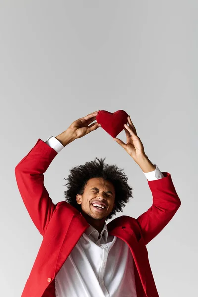 Handsome young man in red attire celebrates with a heart shaped symbol, exuding joy. — Stock Photo