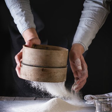 Sifting flour by female hands