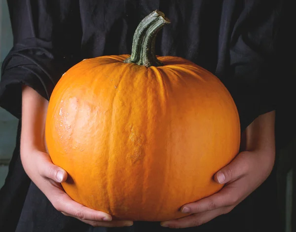 Grote pompoen in kind handen — Stockfoto