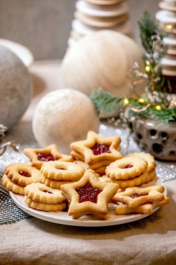 Ev yapımı geleneksel Noel Linz kurabiyeleri ve kırmızı reçelli kurabiyeler. Keten masa örtüsü üzerine ahşap çevre dostu xmas dekorasyonları. Tatil masası ayarı.