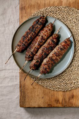 Doğu fast food. Baharatlı ızgara biftek, liulya kebabı. Tahta masada, seramik tabakta, saman peçeteyle. Düz yat, boşluğu kopyala
