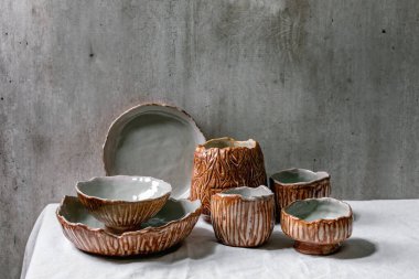 Beyaz keten masa örtüsünde gri duvarlı gri ve kahverengi desenli boş seramik kaseler seti. Boşluğu kopyala.