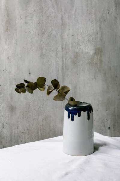 白いリネンのテーブルクロスのセラミック花瓶のユーカリの枝の後ろに灰色の壁 スペースのコピー — ストック写真
