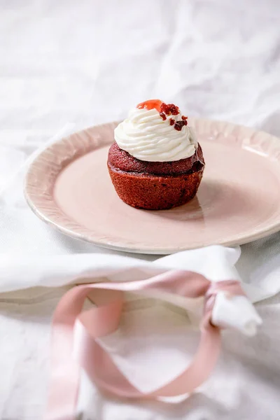 自制红色天鹅绒蛋糕 粉红瓷盘上有奶油 白色餐巾上有丝带 白色亚麻布桌布上有丝带 复制空间 — 图库照片