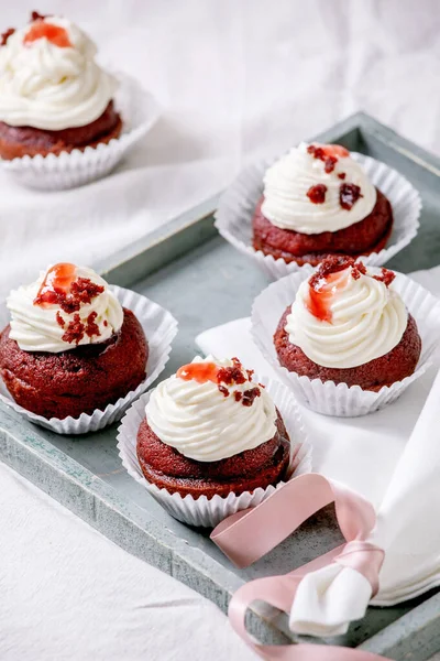 木製のトレイにホイップクリームと自家製の赤いベルベットのカップケーキ 白いリネンテーブルクロスにリボン付きの白いナプキン — ストック写真
