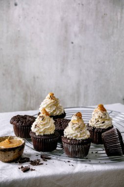 Beyaz krem şantili ve tuzlu karamelli ev yapımı çikolatalı kekler, beyaz masa örtüsü üzerinde doğranmış siyah çikolatalı kekler..