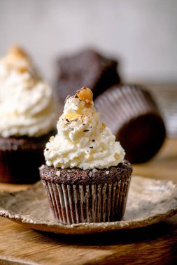 Beyaz krem şantili ev yapımı çikolatalı kekler ve ahşap masada seramik tabakta tuzlu karamel..