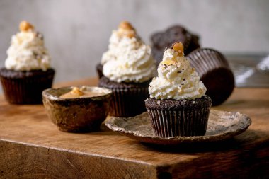 Beyaz krem şantili ev yapımı çikolatalı kekler ve ahşap masada seramik tabakta tuzlu karamel..