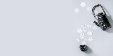 Beyaz kağıt çiçeklerin seramik çaydanlıktan gri arka planda fincana aktığı yaratıcı afiş düzeni. Düz konum, kopyalama alanı. Çiçek çayı, yaz ya da bahar zamanı konsepti