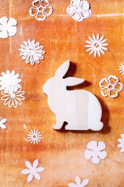 Paskalya tavşanı. Turuncu taş arka planda farklı kağıt çiçekler var. Düz konum, kopyalama alanı. Paskalya bayramı tebrik kartı kavramı