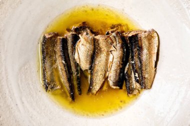 Smoked sardines in oil served in white ceramic plate . Top view, flat lay. Close up