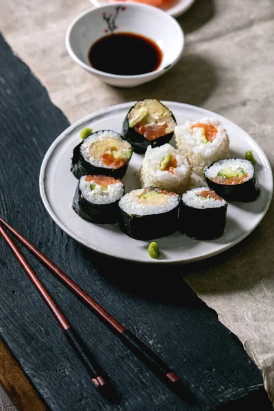 自制寿司卷 配上鲑鱼 日本煎蛋卷 芥末和酱油 配上木制筷子和黑色木制背景的灰纸 日本风格的晚餐 — 图库照片