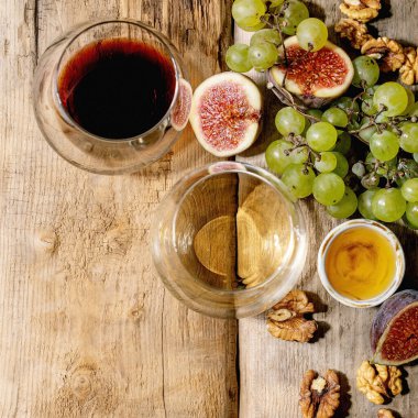 Üzümlü, incirli, keçi peynirli ve cevizli kırmızı ve beyaz şarap eski ahşap arka planda. Düz konum, kopyalama alanı. Kare