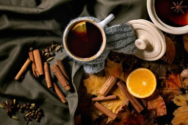 Sıcak sıcak şarap seramik kapta ve eşarplı kupa koyu keten masa örtüsünün üzerinde portakal ve sonbahar yaprakları. Düz yatıyordu. Sıcak bir atmosfer. Düz yatıyordu