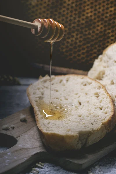Pouring honey on fresh bread — Stock Photo, Image