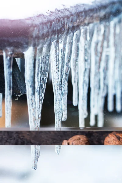 Ijspegels op dak met sneeuw — Stockfoto