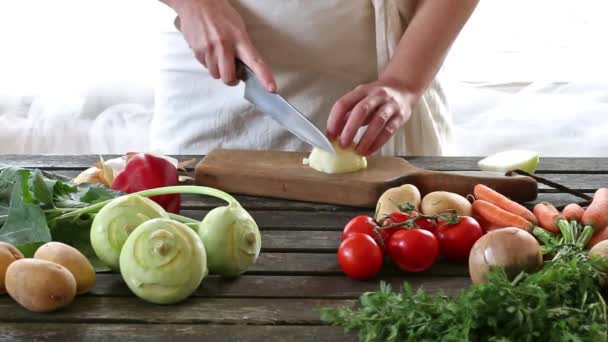 Una mujer corta verduras. Mujer rebanar cebolla en la mesa de madera. Estilo rústico . — Vídeos de Stock