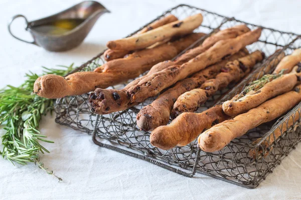 Grissini 빵과 올리브 오일νωπά ψημένα σπιτικό Κριτσίνια Κριτσίνια σε vintage μεταλλικό πλέγμα κουτί με ελαιόλαδο και βότανα δενδρολίβανο και θυμάρι πάνω από την σκοτεινή επιφάνεια — 스톡 사진