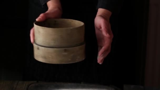 Sieving whole wheat flour through old sieve by woman's hands. Dark rustic style — Stock Video