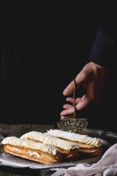 Eclairs auf Metallplatte in Frauenhänden — Stockfoto