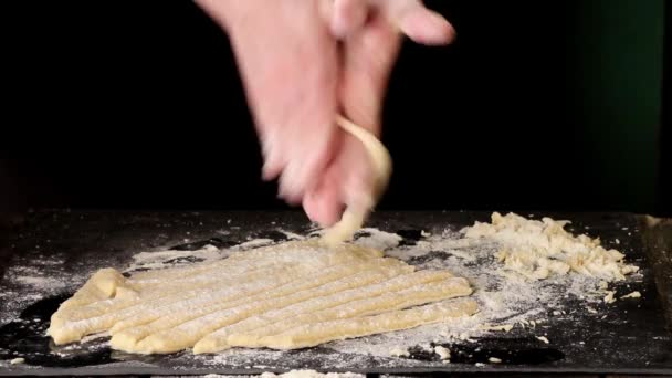 Vrouwelijke handen maken van pasta pici over zwarte keukentafel, poederen door bloem — Stockvideo