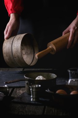 Female hands with wooden rolling-pin and sieve