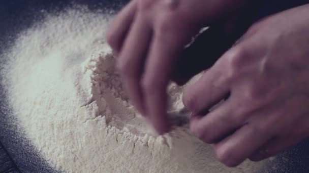 Female hands break the egg into flour for making dough over black table. Dark rustic style. In retro filter effect — Stock Video