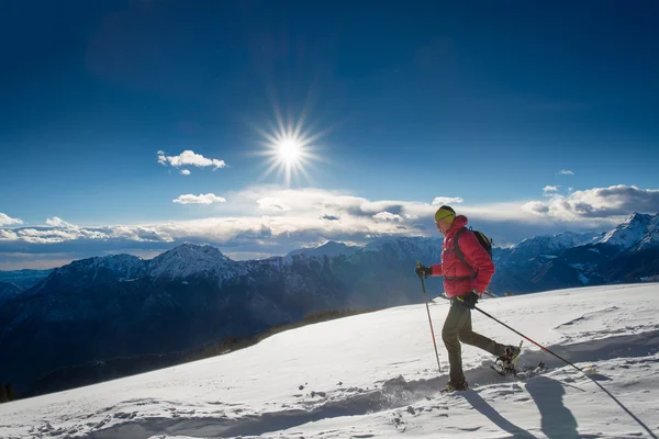 Der Mann in Schneeschuhen und mit Wanderstöcken — Stockfoto