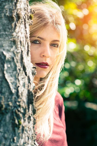 Блондинка за деревом — стоковое фото