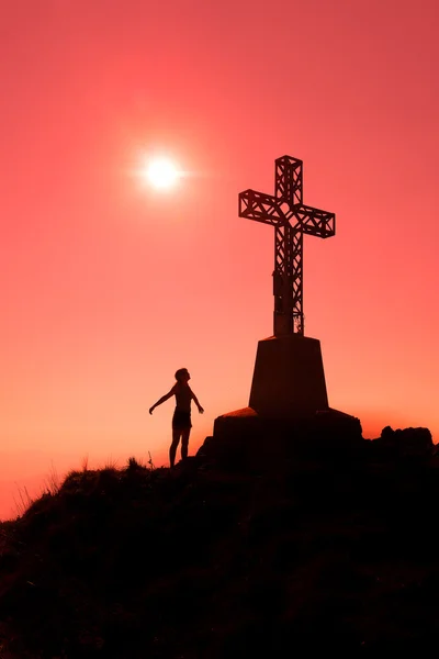 Cross on top of a mountain with open arms woman — Stock Photo, Image