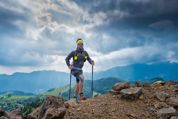 Mannelijke atleet klimt naar een berg achter panorama van de bergen — Stockfoto