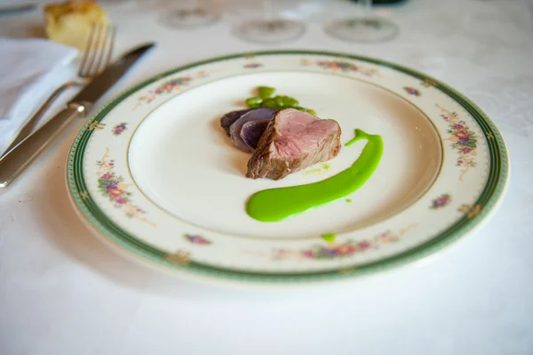 Dish of tenderloin with violet potatoes and green souce of  bean — Stock Photo, Image