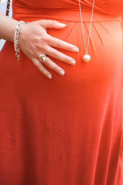 Femme enceinte avec des vêtements rouges et une cloche — Photo