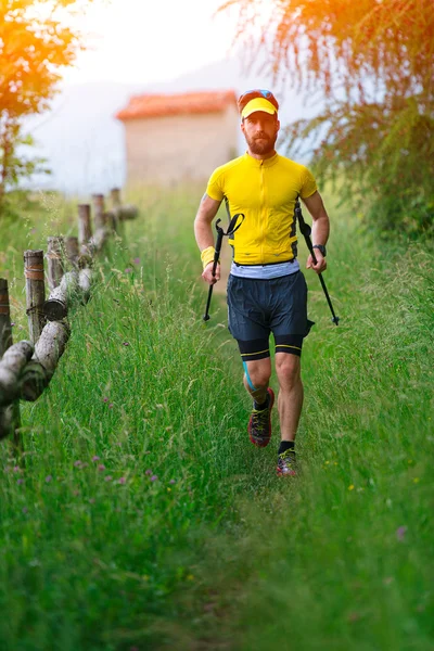 Nordic caminar en la hierba con palos en la mano — Foto de Stock